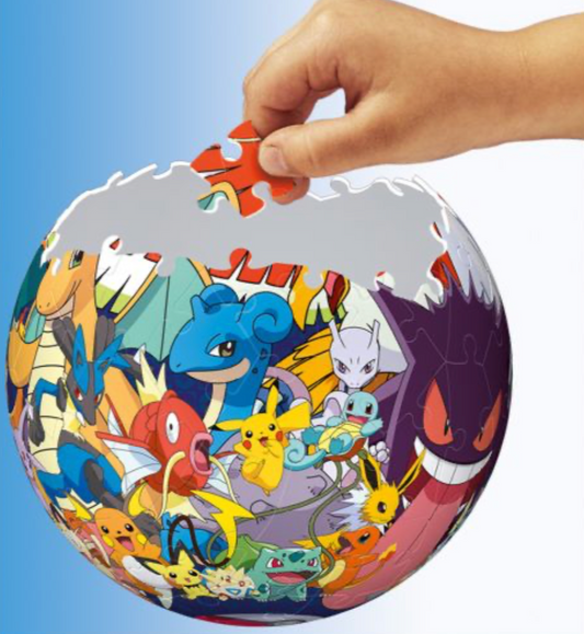 Photo of a hand placing a puzzle piece onto a partially completed Pokémon 3D puzzle sphere. The sphere is mounted on a black stand and shows characters like Charizard, Pikachu, Gengar, and Mewtwo among others. The background is a gradient of blue, and the puzzle piece being added is red, fitting into the top of the sphere